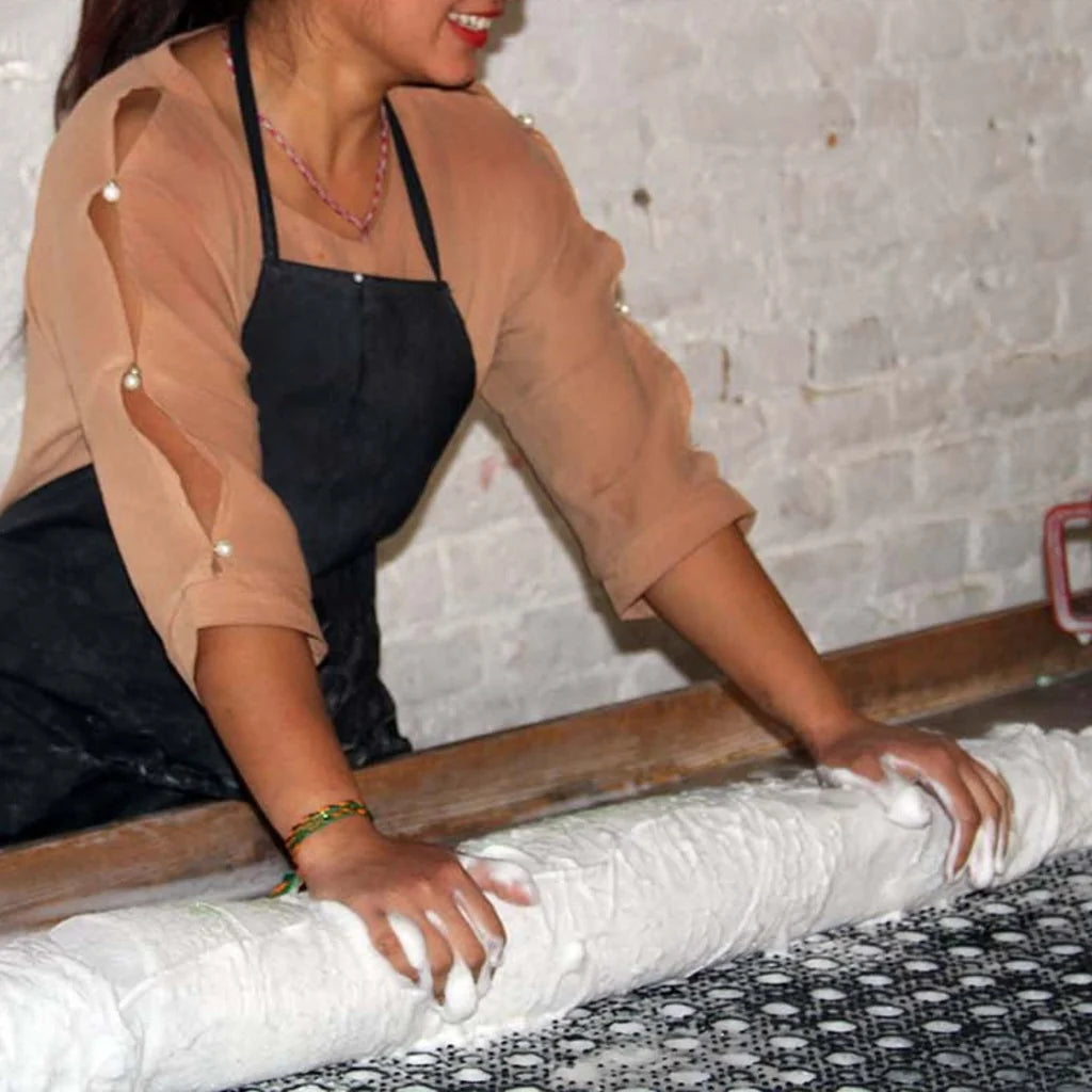 Person showing process of rolling out felt on a textured mat surface with a white brick wall background