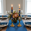 Hand-painted South African Durra design taper candles in blue, orange and white lit in brass holders on an elegant dinner table
