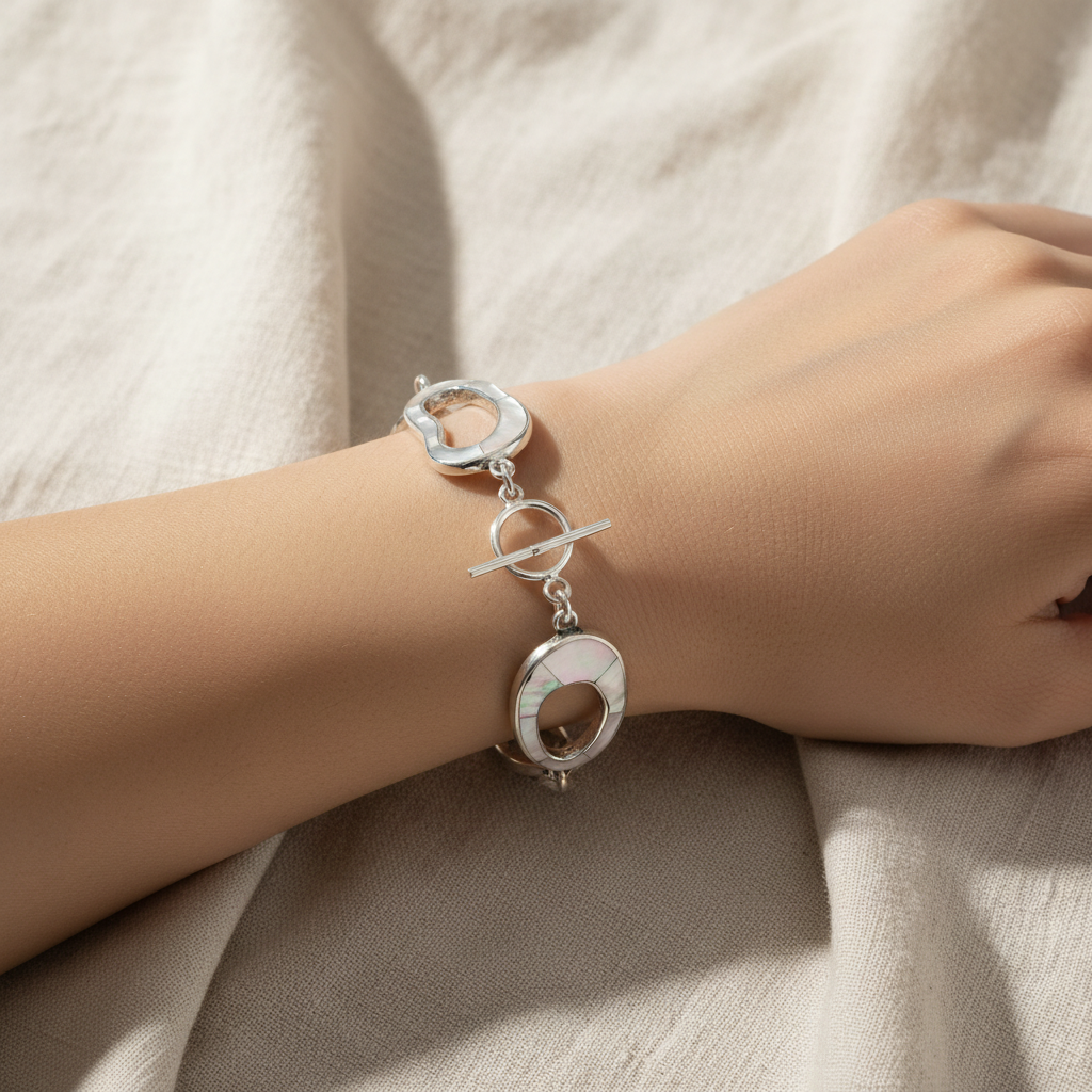 Mother-of-pearl circle link bracelet with silver toggle clasp worn on a woman's wrist