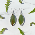 Natural leaf in resin teardrop earrings shown as a pair flat lay on white marble with small fern fronds