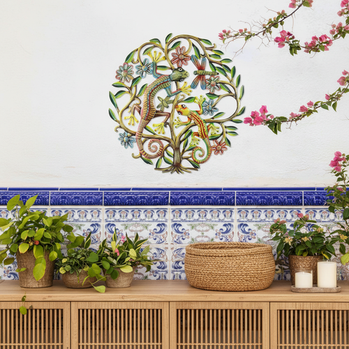 24-inch hand-painted metal gecko tree of life wall art hung on a warm white interior wall above a boho console table with plants and candles