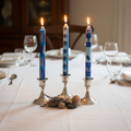 Hand-painted South African Feruzi design tall taper candles in blue and white lit in silver holders on an elegant dinner table