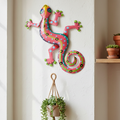 Eight inch pink metal gecko wall art hung on a warm white textured plaster wall in a boho home interior
