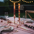 Hand-painted South African Halisi design taper candles in pink, burgundy and cream lit in rose gold holders on a romantic dinner table